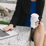 close-up-woman-s-hand-with-disposal-cup-using-laptop